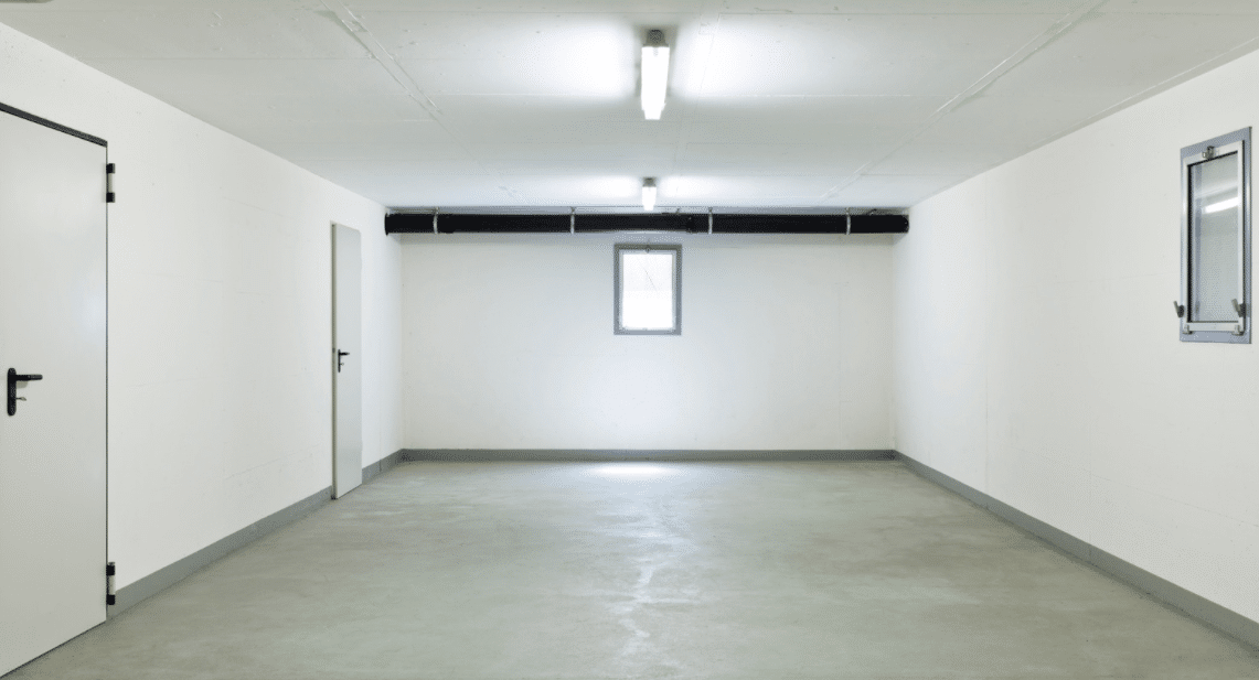 Empty basement with beige floor and white walls.