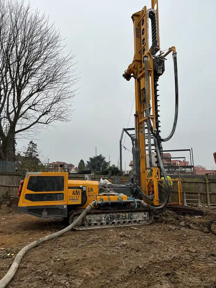 Piling rig hire | A yellow piling rig in a construction field.